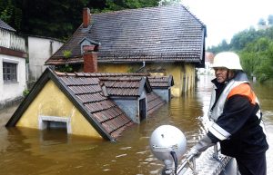 Feuerwehrmann vor dem überschwemmten Gasthaus "Zur Fels'n"
