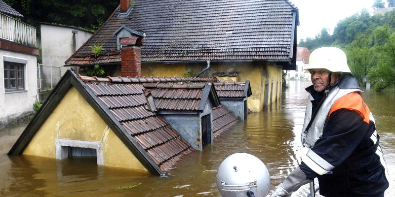 Feuerwehrmann vor dem überschwemmten Gasthaus "Zur Fels'n"