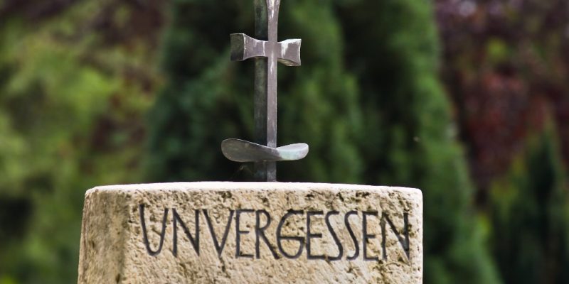 Grabstein mit Kreuz und Inschrift "Unvergessen"