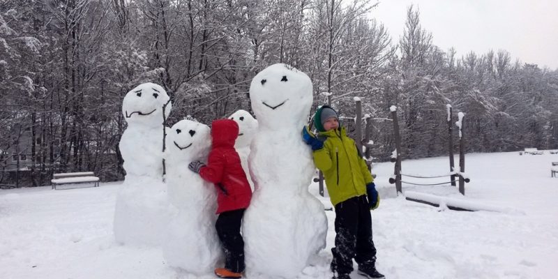 Kinder bauen Schneemänner